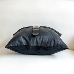 Detailed close-up of a black faux leather throw pillow cover with chic center buckle accent.
