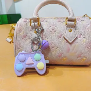 Primo piano del mini portachiavi con giocattolo antistress a forma di gamepad viola pastello.