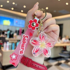 Detailed close-up view of the clear liquid quicksand flower keychain pendant with pink strap.