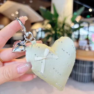 Close-up of a charming satin heart keychain with sparkling rhinestones and a sweet bow detail.