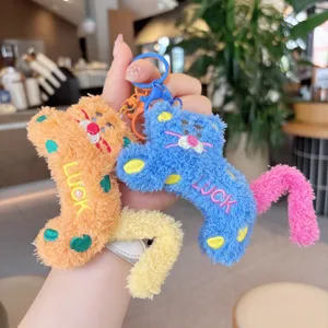 Detalle cercano y detallado del llavero de leopardo de peluche con lunares y bordado.