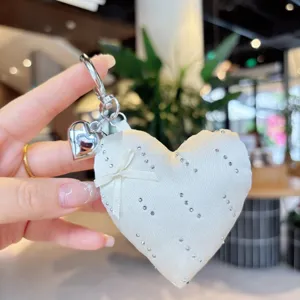 White satin heart bag charm with bows and rhinestones detail close-up view accessory