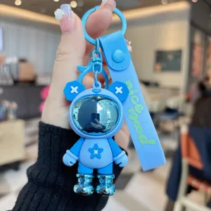 Primer plano del llavero astronauta de PVC azul, con casco brillante y correa de silicona.