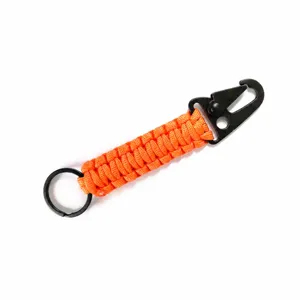 Primer plano detallado del llavero de supervivencia artesanal de paracord naranja con mosquetón.