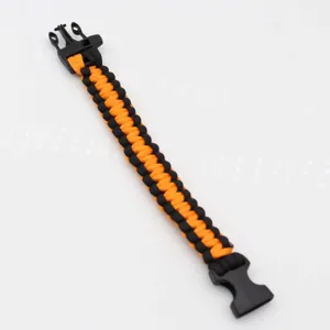 Black and orange paracord survival bracelet detail, durable outdoor gear with plastic buckle.