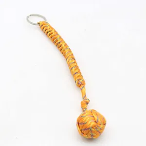 Détail de porte-clés poing de singe en paracorde orange tressée avec anneau métallique robuste.