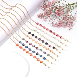 Detailed close-up of colorful crystal heart glasses chain, elegant mask strap with golden metal links.