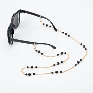 Vista detallada de la cadena dorada para gafas con cuentas negras elegante para mascarillas.