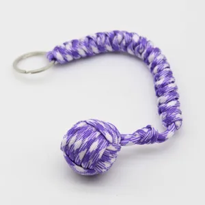 Vue détaillée du porte-clés poing de singe en paracorde violette et blanche avec anneau.