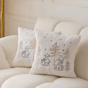 Detailed shot of fluffy white Christmas embroidered throw pillow with winter house pattern.