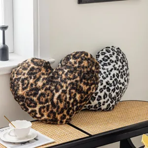 Close-up of fluffy leopard print heart pillows displayed on a woven bench in a cozy home setting.
