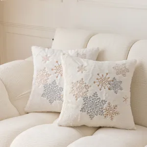 Detailed shot of plush white decorative pillow featuring elegant gold and silver snowflake embroidery.
