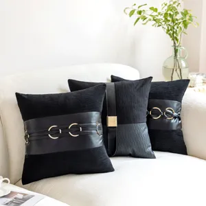 Black decorative throw pillow detail, featuring luxury leather strap and gold ring buckle.