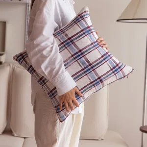 Detailed close-up view of a classic plaid cushion cover shown in a cozy living room setting.