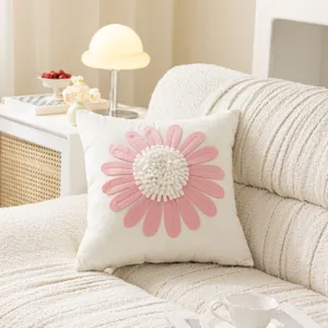 Close-up detail of the decorative pink flower cushion cover on a cozy living room sofa.
