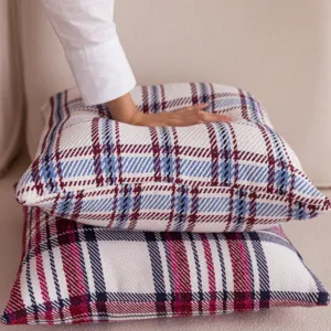 Close-up of cozy plaid throw pillow detail, soft textured fabric on neutral sofa background.