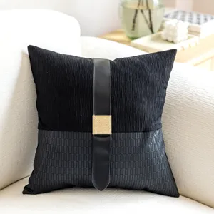 Modern black decorative throw pillow with faux leather strap and chic gold square buckle detail.