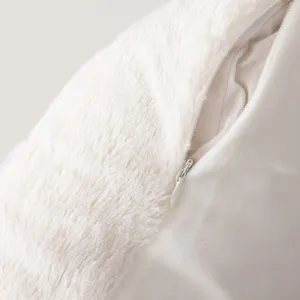 White plush pillow cover detail close-up, soft furry fabric texture with hidden zipper close.