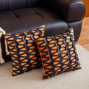 Vista detallada y cercana del cojín de sofá decorativo tejido en color naranja y negro.