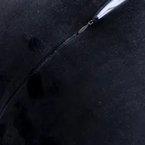 Detailed view of the black plush pillow cover showing the neat zipper and soft fabric texture.