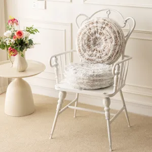 Detailed view of luxury round plush throw pillows with tree-ring texture on a vintage white chair.