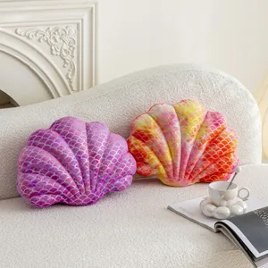Detailed view of soft shell-shaped plush pillows with shimmering silver scale texture on couch.