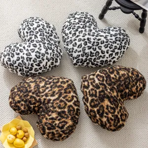 Detailed view of soft leopard print heart-shaped pillows on carpet, cozy home decor lifestyle.
