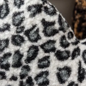 Close-up detail of soft black and white leopard print fleece fabric pillowcase texture.
