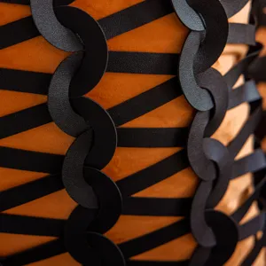 Primer plano detallado de funda de cojín decorativa en negro y naranja con patrón tejido.