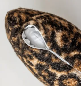 Detail shot of soft fleece leopard print cushion cover showing zipper and plush furry texture.