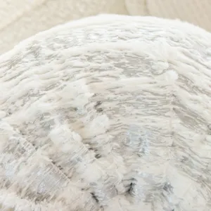 Close-up detail of white and silver faux fur plush fabric cushion texture, soft and fluffy.
