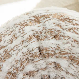 Close-up detail view of luxury white faux fur cushion cover with golden tree ring pattern texture.