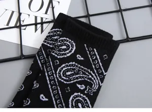 Detail view of black cotton socks featuring a classic white paisley pattern for streetwear.