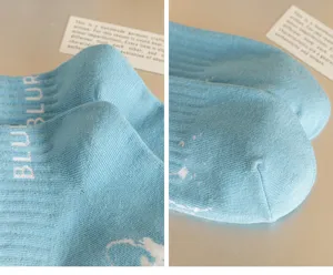 Close-up detail of light blue cotton socks with letter knit and white splatter design style.