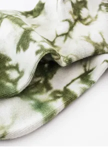 Dettaglio di calzini in cotone tie-dye verde e bianco, trama morbida e motivo unico.