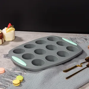Détail de moule à muffin en silicone avec 12 cavités et poignées menthe sur table décorée.