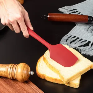 Vue de detail de la spatule en silicone etalant doucement la creme sur du pain.