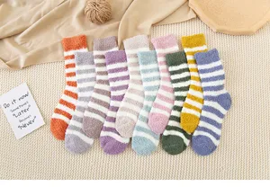 Detailed close-up of colorful striped coral fleece cozy home socks laid flat on cozy knit fabric.