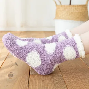 Women fluffy coral fleece cozy socks with white polka dot design for winter home wear.