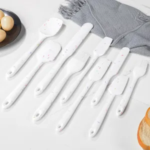 Detail des Silikon-Spatel-Sets mit bunten Streuseln auf weissen Kuechenutensilien.