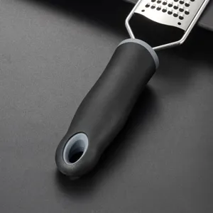 Dettaglio grattugia formaggio acciaio inox, manico nero ergonomico, zester da cucina primo piano
