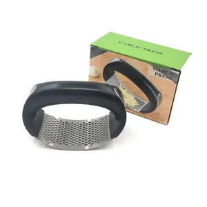 Stainless steel curved garlic press with black handle and green packaging box for kitchen.