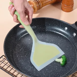 Detail view of a wide silicone spatula in a frying pan, ideal for cooking meals.