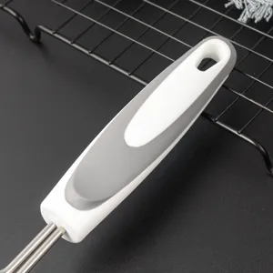 Vue rapprochée de la poignée ergonomique d'ustensile de cuisine blanc et gris avec trou de suspension.