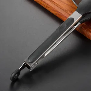 Dettaglio pinza da cucina in acciaio inox, impugnatura in silicone nero, utensile BBQ.