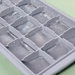 Gros plan de détail du bac à glaçons en silicone gris rempli de glaçons transparents.