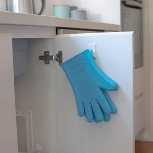 Dettaglio guanto da forno in silicone blu appeso in cucina moderna, strumento resistente al