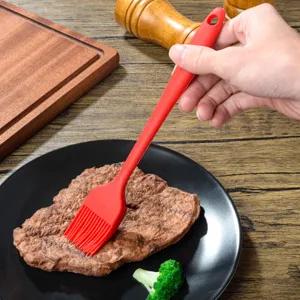 Silicone basting brush in use, showing flexible bristles and ergonomic handle detail.