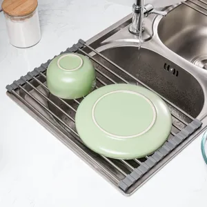 Roll-up stainless steel silicone dish drying rack over kitchen sink for space-saving storage.
