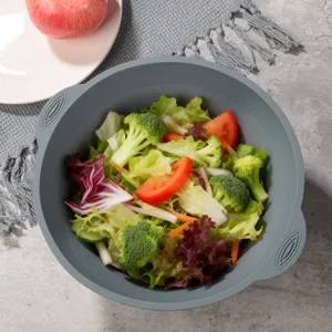 Detailed shot of grey foldable silicone salad bowl filled with fresh vegetables, kitchen tool.